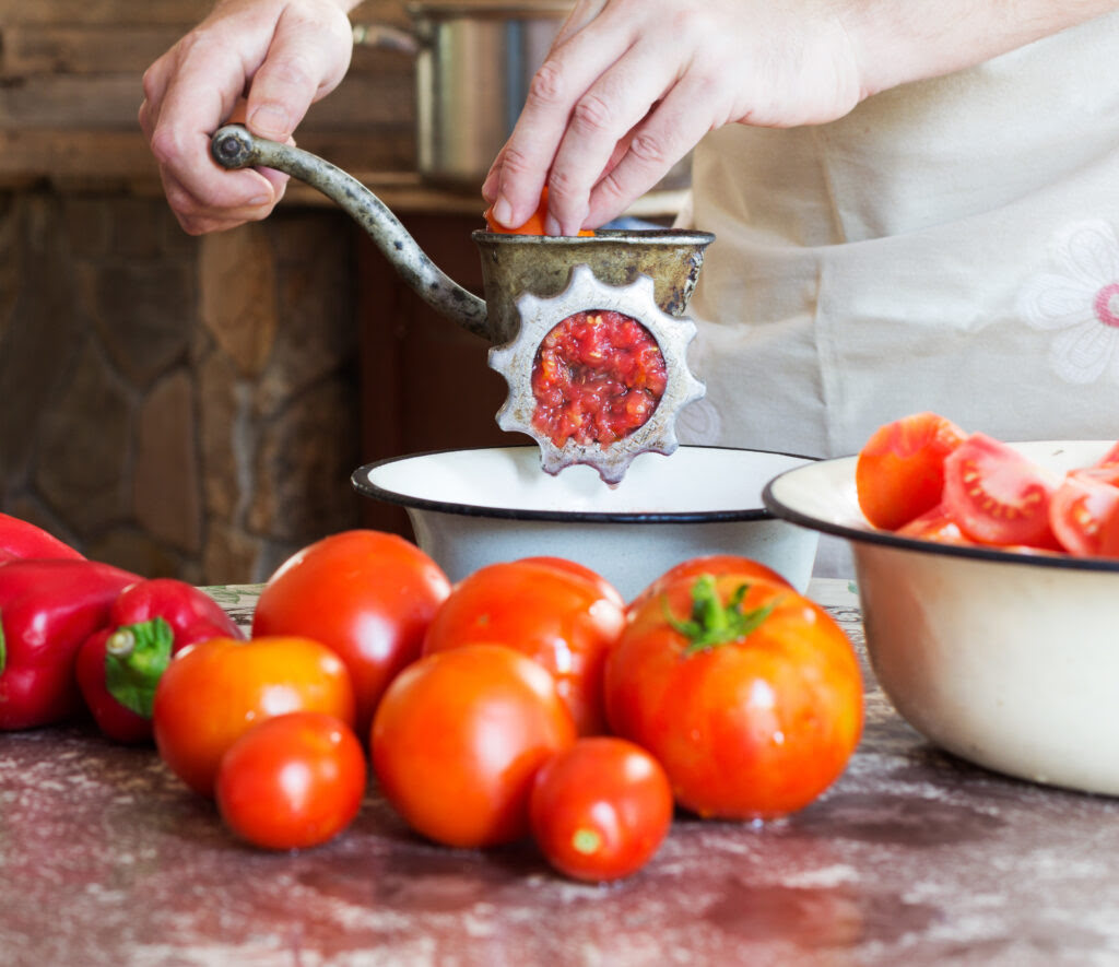  Mielenie pomidorów maszynką ręczną nad miską 