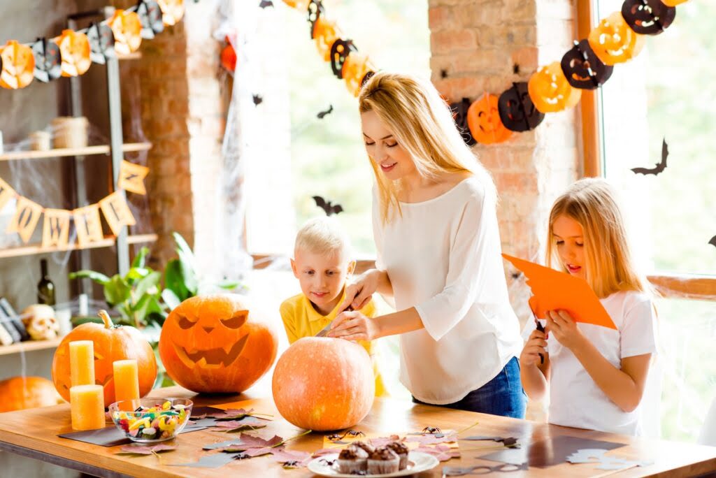 Kobieta i dzieci wycinają dynię na Halloween