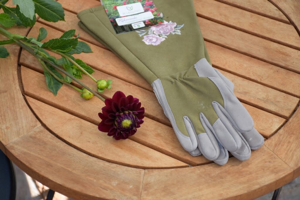 Długie rękawice ogrodowe i kwiat dalii leżące na stole