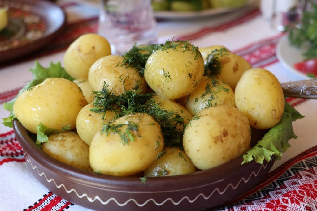 Gotowane ziemniaki polane masłem i posypane koperkiem